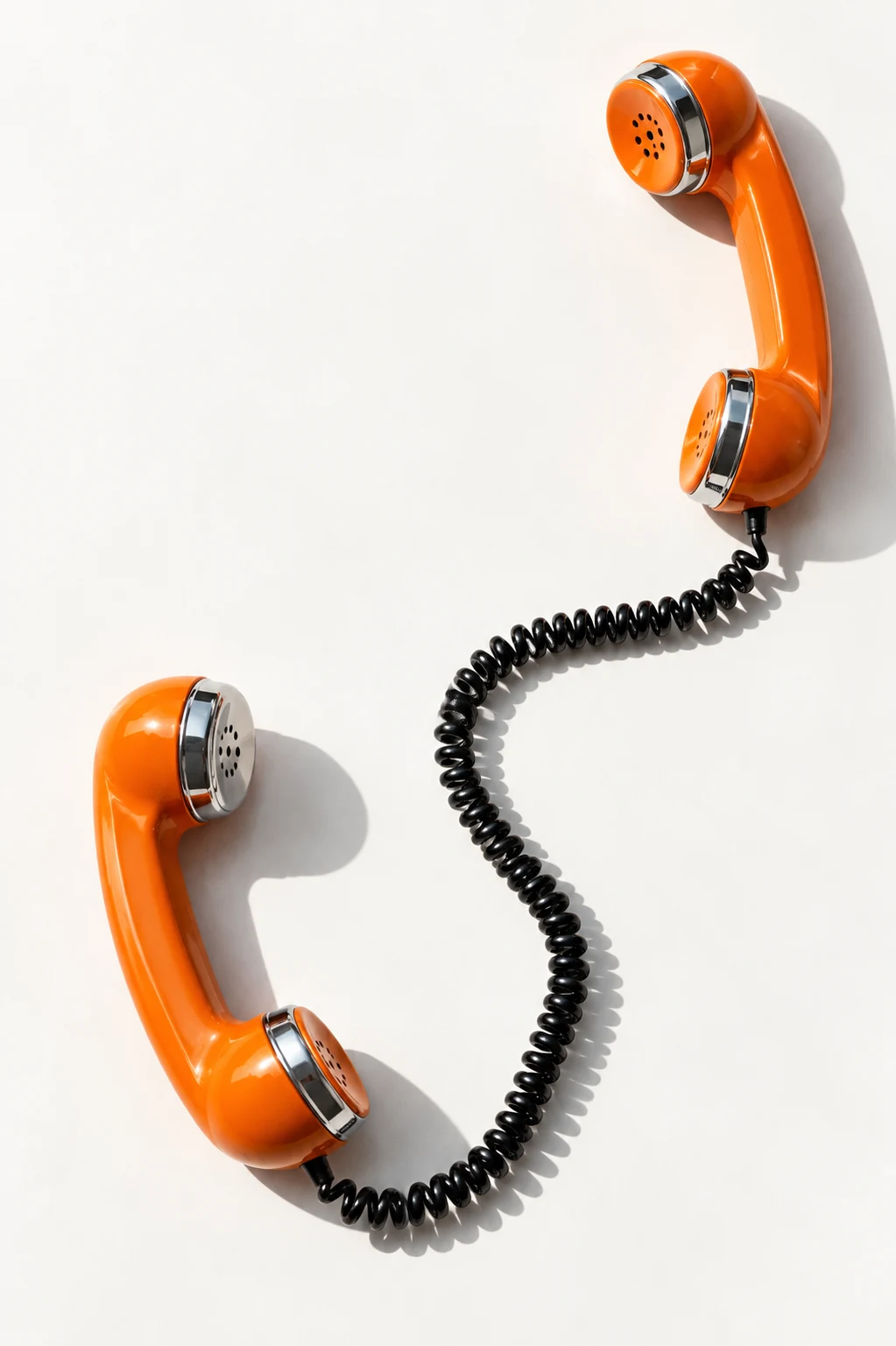 Two orange telephone receivers connected by a loosely curved black cord.